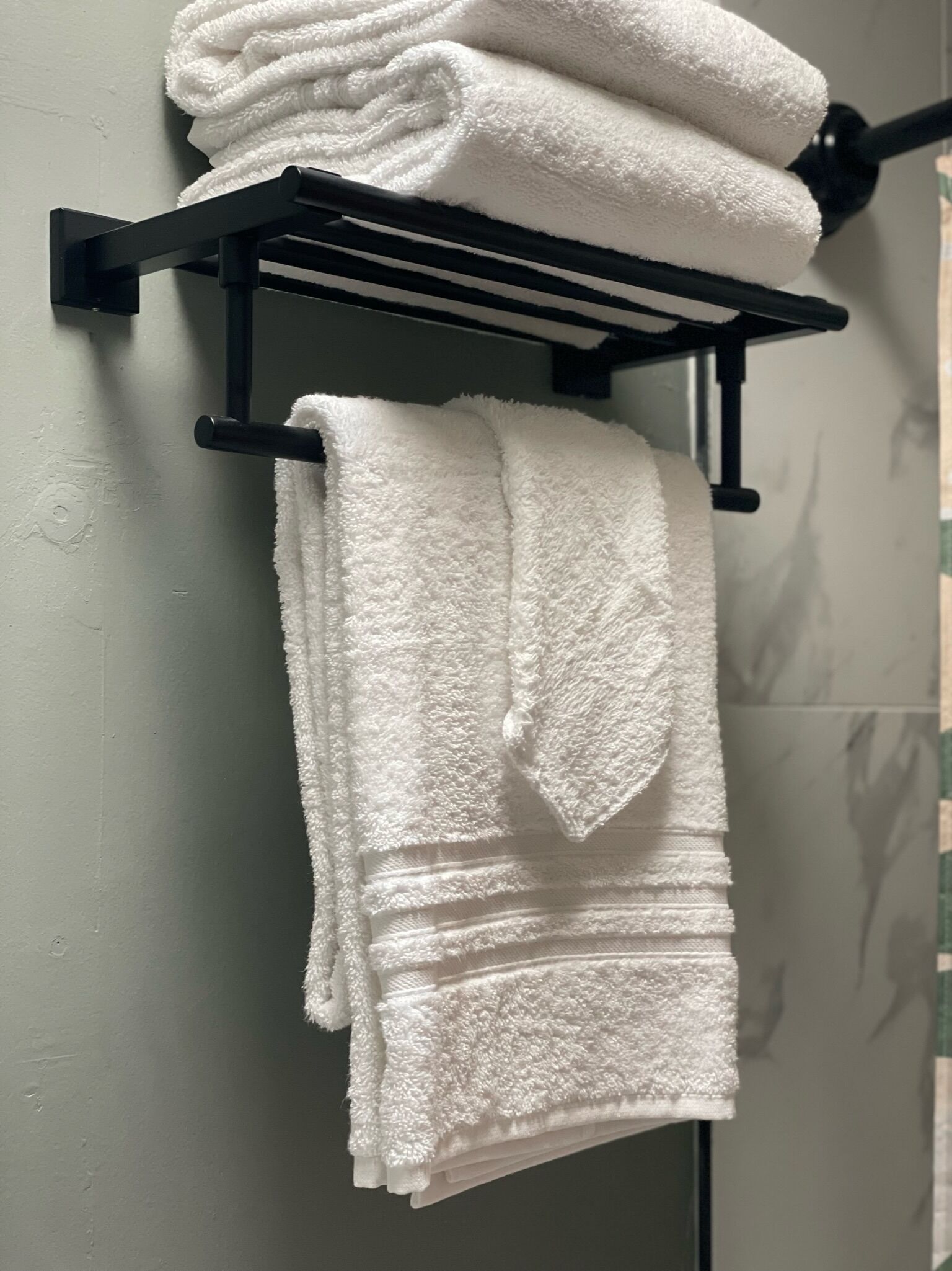 A bathroom with a towel rack holding two folded white towels.