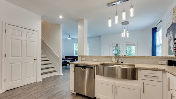 A modern kitchen with white cabinets, a stainless steel dishwasher, and pendant lighting. - Elegant Atlanta Home - Self Check-in (Atlanta)