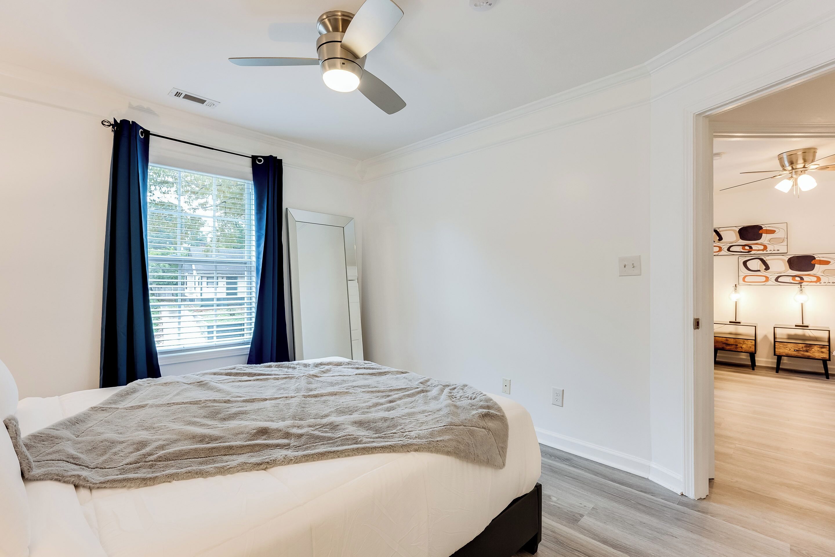 Ein Schlafzimmer mit Bett, Deckenventilator und Blick auf den Flur.