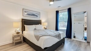 A modern bedroom with a bed, bedside lamps, a ceiling fan, a framed picture, and a door with a mirror. - Elegant Atlanta Home - Self Check-in (Atlanta)