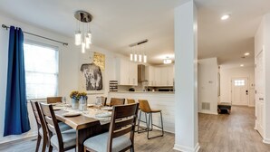 A modern kitchen with white cabinets, a central island, and pendant lighting. - Elegant Atlanta Home - Self Check-in (Atlanta)