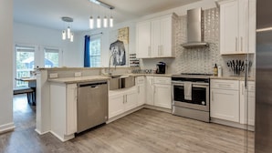 A modern kitchen with white cabinetry, stainless steel appliances, and a large island. - Elegant Atlanta Home - Self Check-in (Atlanta)
