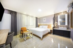A hotel room with a bed, a desk, a chair, a bathroom with a sink and mirror, and curtains. - Browndot Angang (Gyeongju)