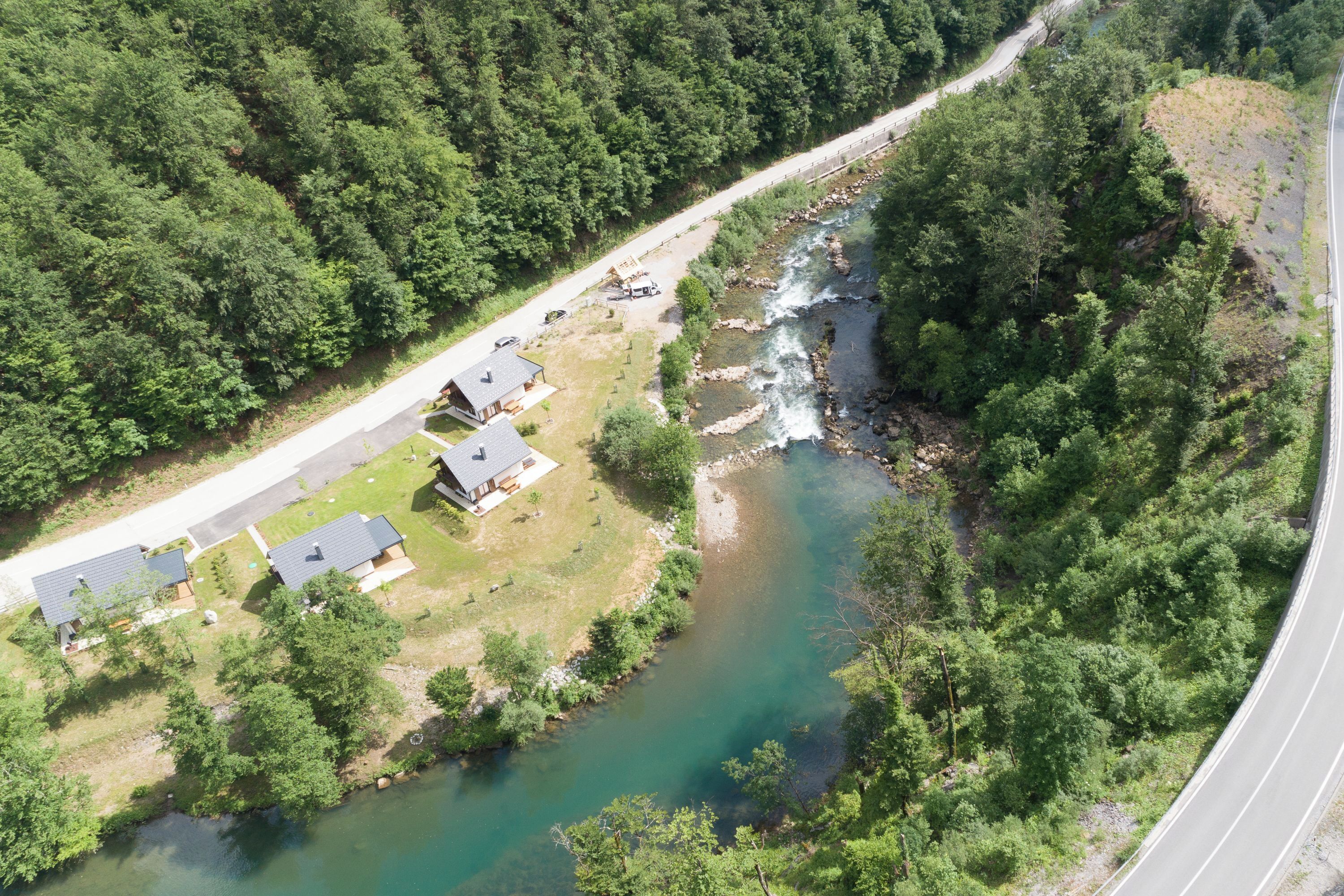Vue aérienne d’une propriété riveraine comprenant plusieurs maisons, une route et un pont.