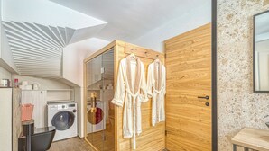 Un baño moderno con tocador de madera, lavadora y perchero con batas.