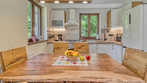 Una cocina moderna con armarios de madera, una isla central y una mesa de comedor con frutero.