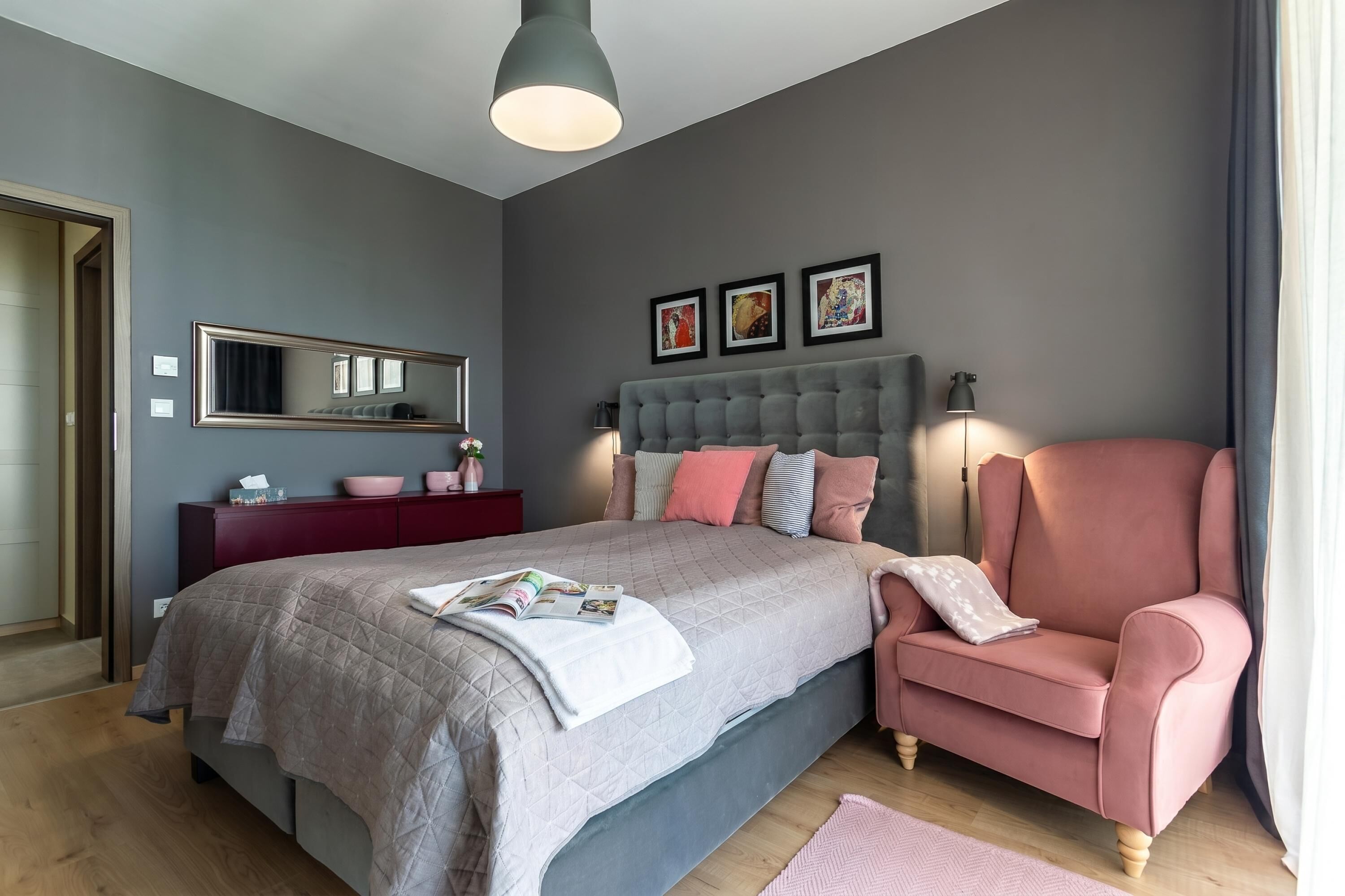 Ein Schlafzimmer mit Bett, Stuhl, Schminktisch und Wandbildern.