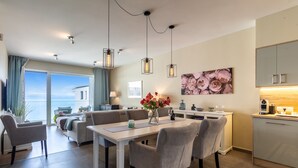 Ein modernes Wohnzimmer mit Essbereich, großen Fenstern und einer Küche mit Blick.