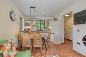 Une cuisine moderne avec un coin repas, des meubles en bois et une horloge bien visible au mur.