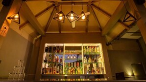 A bar area with a wooden ceiling and hanging pendant lights. There is a well-stocked bar counter with various bottles and glasses. - The Porto by Lagom (Vagator)