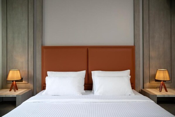 Una habitación de hotel con una cama grande, dos mesitas de noche y un cabecero de madera.