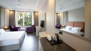 A hotel room with a bed, a desk, a chair, a TV, and a large mirror. - The Porto by Lagom (Vagator)