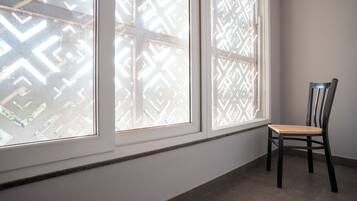 A room with a window, a chair, and a patterned window blind.