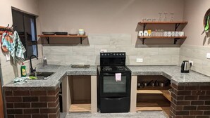 Eine kleine Küche mit Einbauofen, Granit-Arbeitsplatten und Holzregalen darüber.