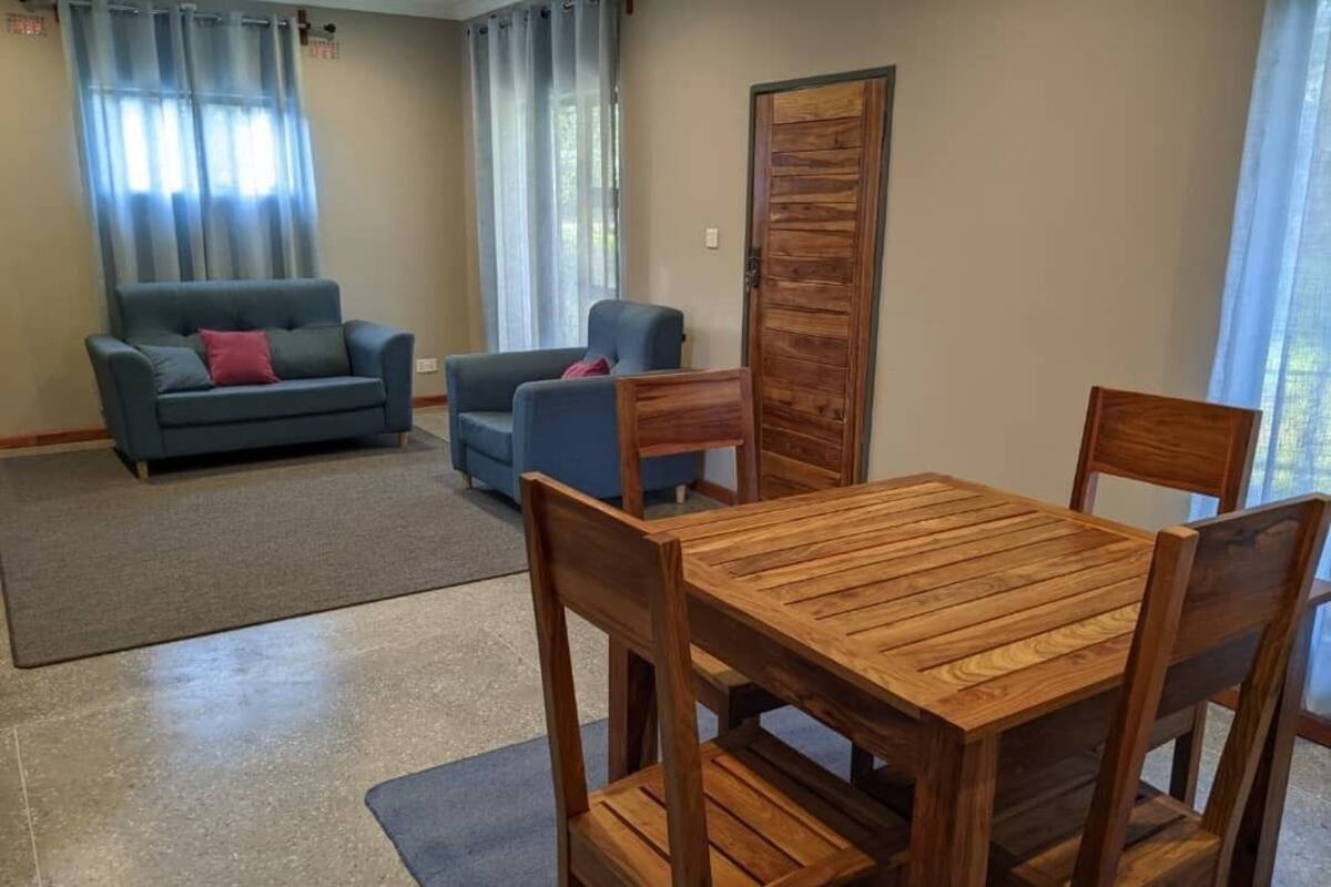 A room with a wooden dining table and chairs, a blue sofa, and a wooden partition.