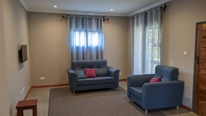 Ein Wohnzimmer mit zwei blauen Sesseln, einem grauen Sofa und einem kleinen Holztisch.