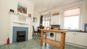 Een keuken met een ingebouwde wasmachine, een houten tafel en een open haard.