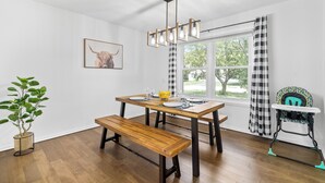 En spiseplads med et træbord, bænk og et højt loft med synlige bjælker.