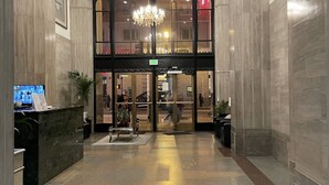 A hotel lobby with a reception desk, a chandelier, and a large arched entrance. - Iconic Heart of DTLA Loft with Rooftop Pool/Jacuzzi/Skyline (Los Angeles)