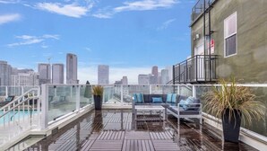 A rooftop terrace with a glass balustrade, a pool, a sofa, and a potted plant. - Iconic Heart of DTLA Loft with Rooftop Pool/Jacuzzi/Skyline (Los Angeles)