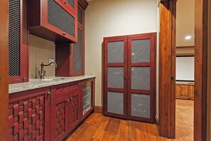 A kitchen with red cabinetry, a sink, and a wooden floor.