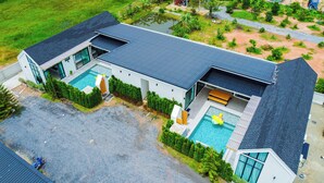 Una casa moderna con una amplia piscina, un porche cubierto y un jardín bien cuidado.