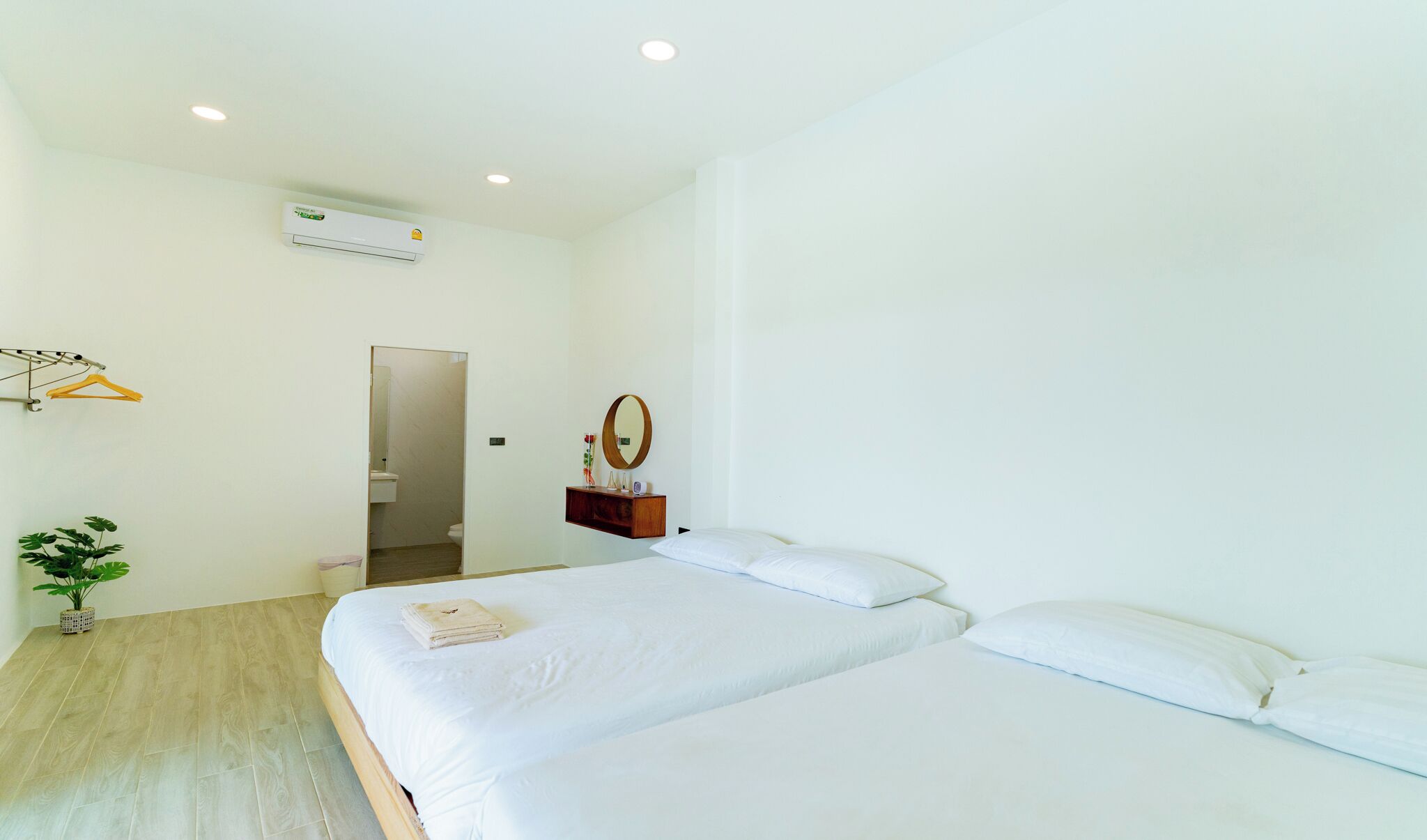 Ein modernes Hotelzimmer mit einem großen Bett, einem kleinen Nachttisch, einem Spiegel und einer Wand-Klimaanlage.