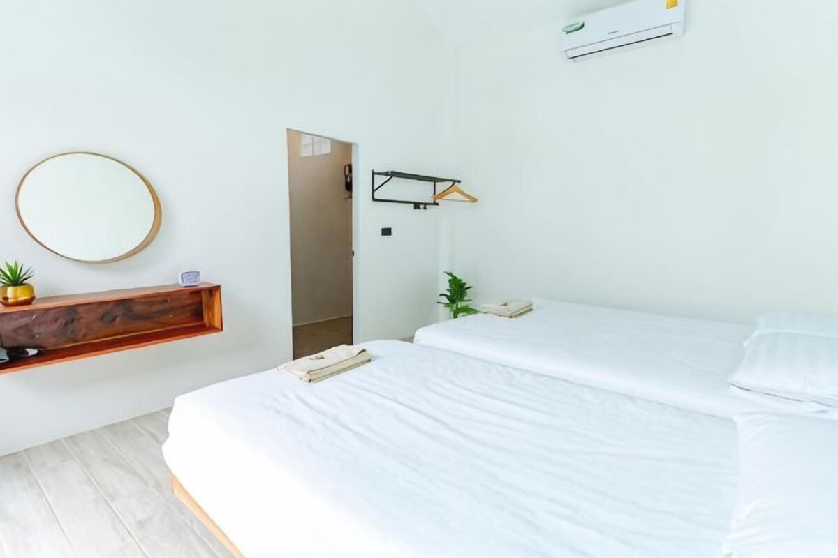 Un dormitorio con una cama, una mesita de noche, un espejo y un aire acondicionado instalado en la pared.