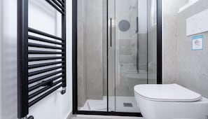 A modern bathroom with a glass shower enclosure, a white toilet, and a towel rack.