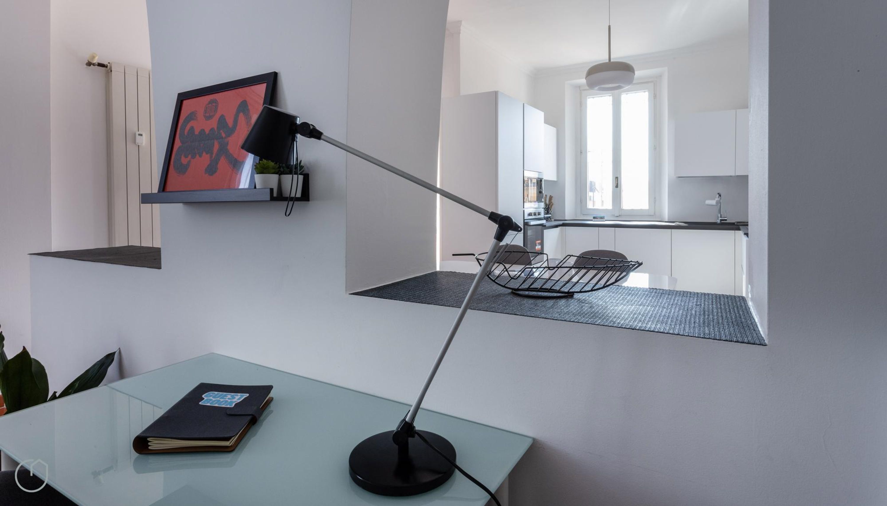 A modern kitchen with white cabinets, a black countertop, and a hanging light fixture.