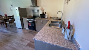 A compact kitchen with a gas stove, microwave, and double sink. - Chalet in Batrouna Park resort, facing the pool, gazon,gym,GENERATOR IS INCLUDED (Helweh)