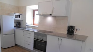 A modern kitchen with white cabinets, a built-in microwave, a stove, and a coffee machine. - Cottage with 2 bedrooms with both en-suite bathrooms in a seaside village (Salir do Porto)