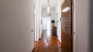 A hallway with wooden flooring, white walls, and a door on the right.