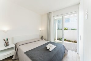 Un dormitorio moderno con una cama, mesitas de noche y vistas a un balcón.