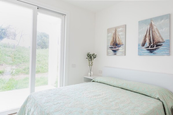 Un dormitorio con cama, ventana y dos cuadros de veleros.