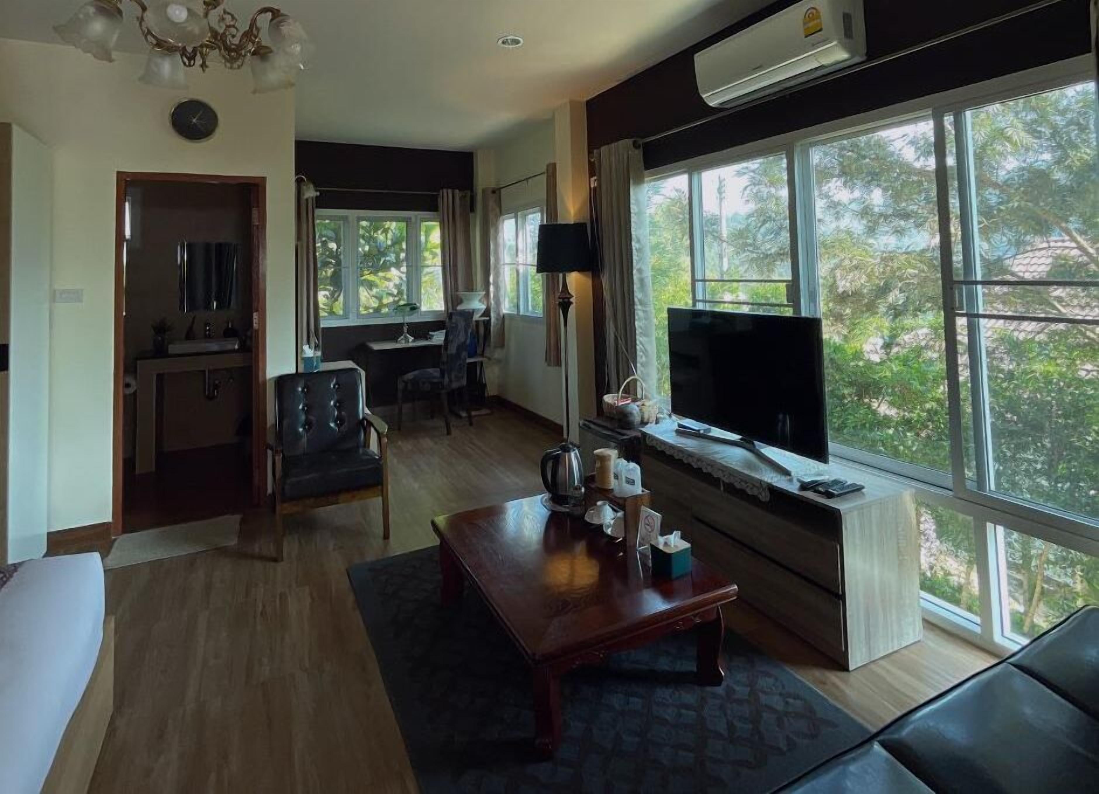 Un salon avec un canapé, une table basse, un téléviseur et une fenêtre donnant sur des arbres.