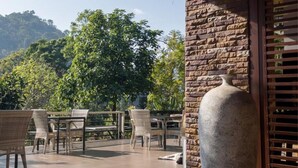 An outdoor patio with wicker furniture and a large stone vase.