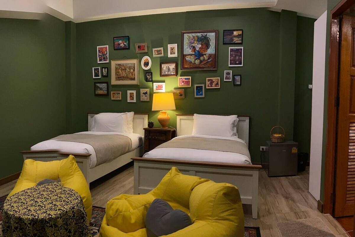 A room with two beds, a small round table, and a lamp.