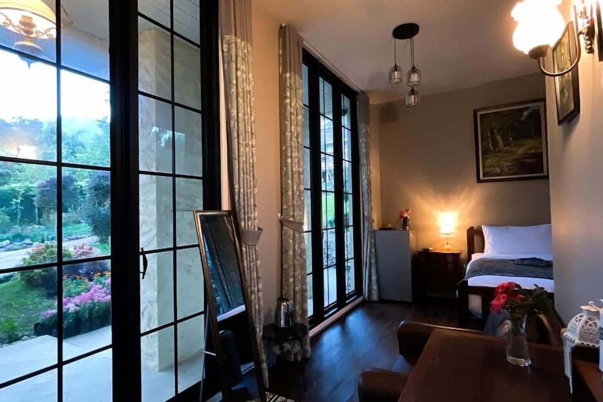 A hotel room with large windows, a bed, a desk, and a chair.