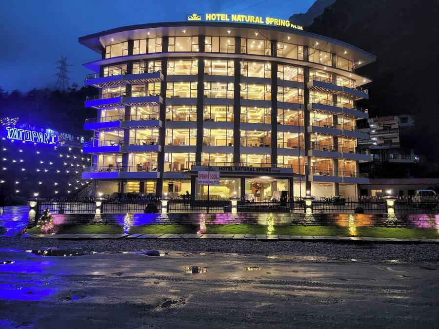 Ein mehrgeschossiges Hotel mit einer geschwungenen Fassade, beleuchteten Fenstern und einem Schild, das die bevorstehende Eröffnung ankündigt.