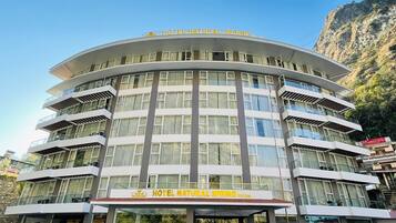 A multi-story hotel with balconies and large windows, named "Hotel Natural Spring."