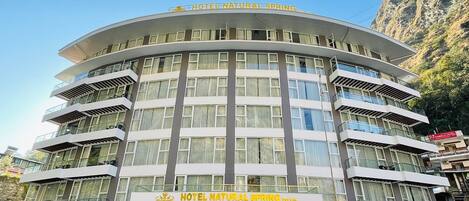 A multi-story hotel with balconies and large windows, named "Hotel Natural Spring."