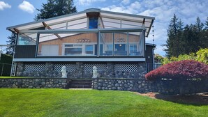 A modern two-story house with a stone foundation, large windows, and a visible garage. - Lakefront House with dock and lots of toys! (Stanwood)