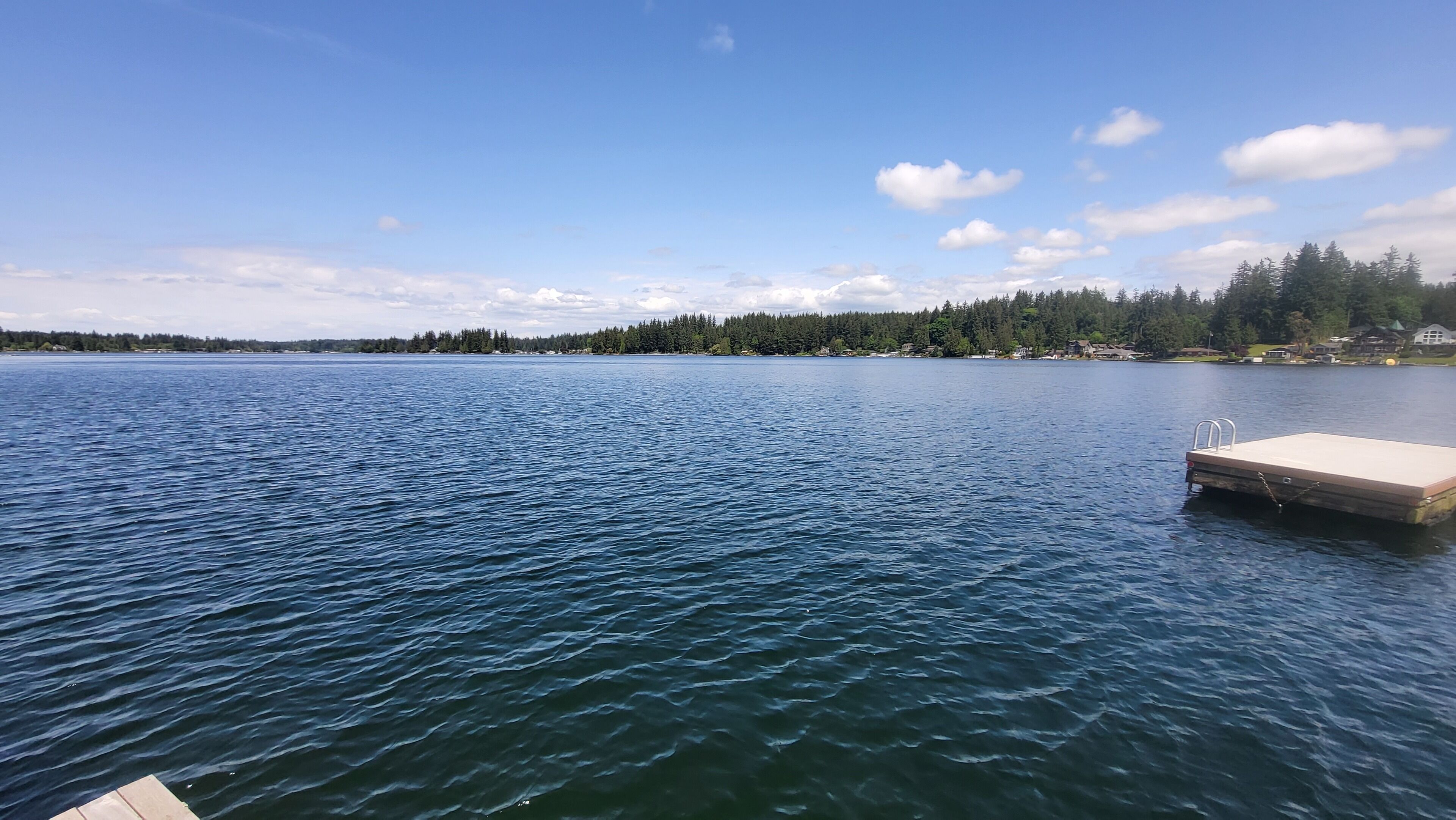 Un lac paisible avec une jetée en bois qui s’avance sur l’eau.
