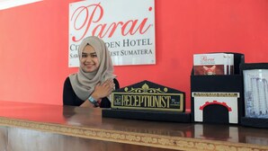 A reception desk with a sign for Parai City Garden Hotel, a receptionist badge, and a menu stand. - Jalan Bagindo Aziz Chan (Saringan)
