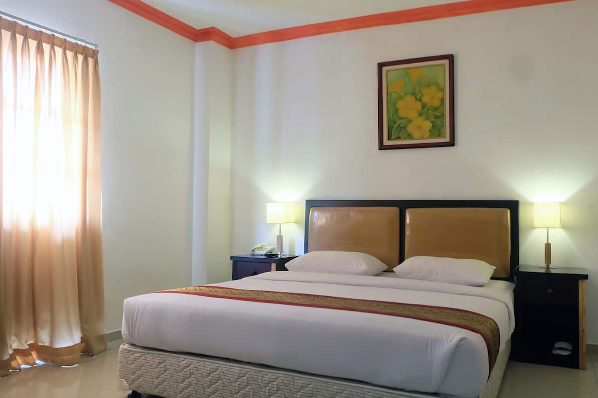 A hotel room with a bed, two bedside tables, a lamp, a chair, and a painting on the wall.