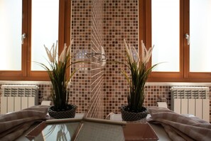 A bathroom with a glass shower enclosure, a tiled wall, and two potted plants. - Sogno di Mare in Lido Riccio (Ortona)
