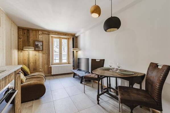 Un'accogliente sala da pranzo con un tavolo e sedie in legno, una televisione e una finestra vista.