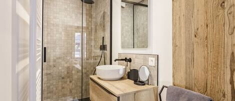 A modern bathroom with a glass-enclosed shower, a wooden vanity, and a large mirror.