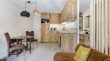 Una cucina moderna con mobili in legno, un'area pranzo con tavolo e sedie, e un divano con un cuscino decorato.
